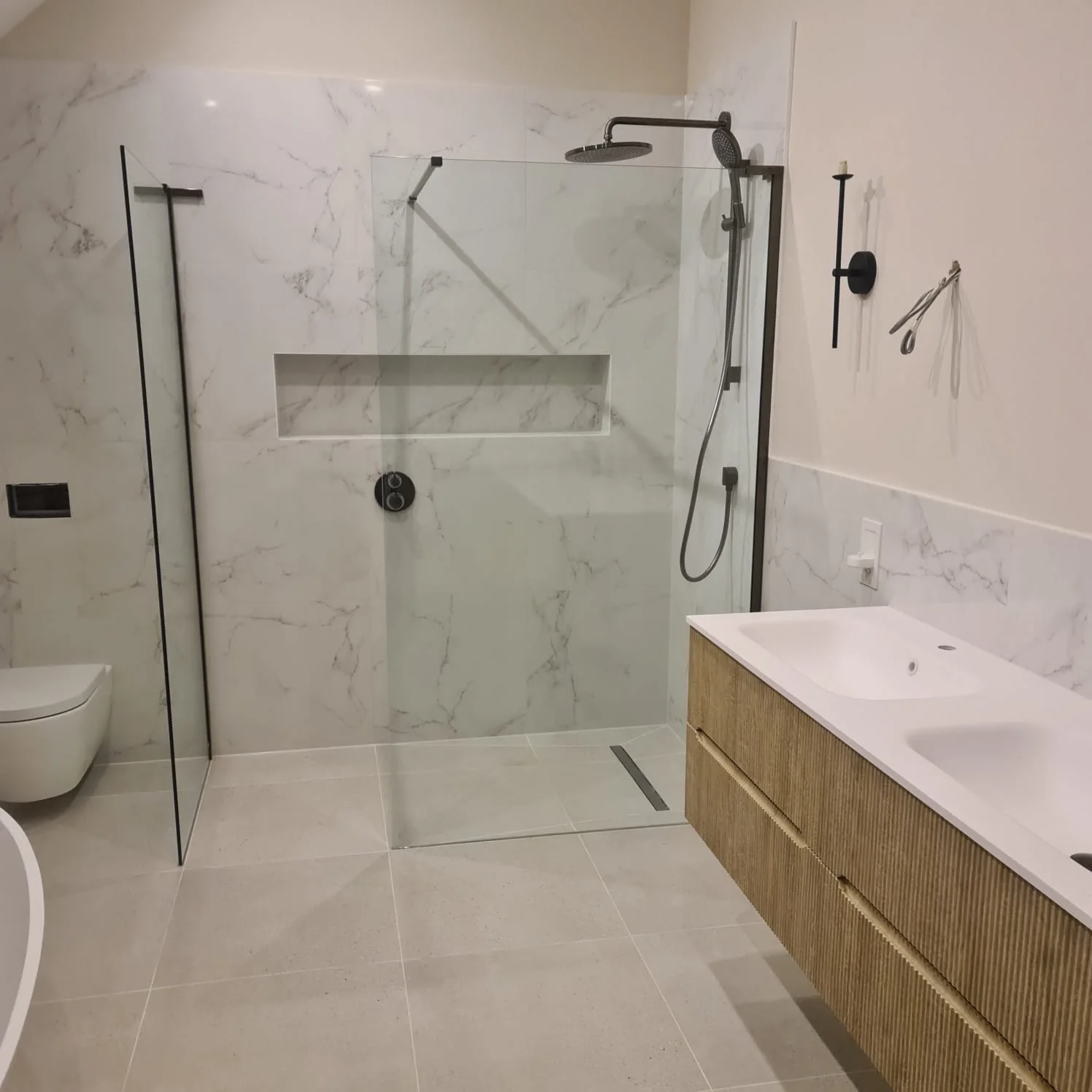 Marble-effect en-suite with a walk-in shower, black fittings and a fluted timber vanity
