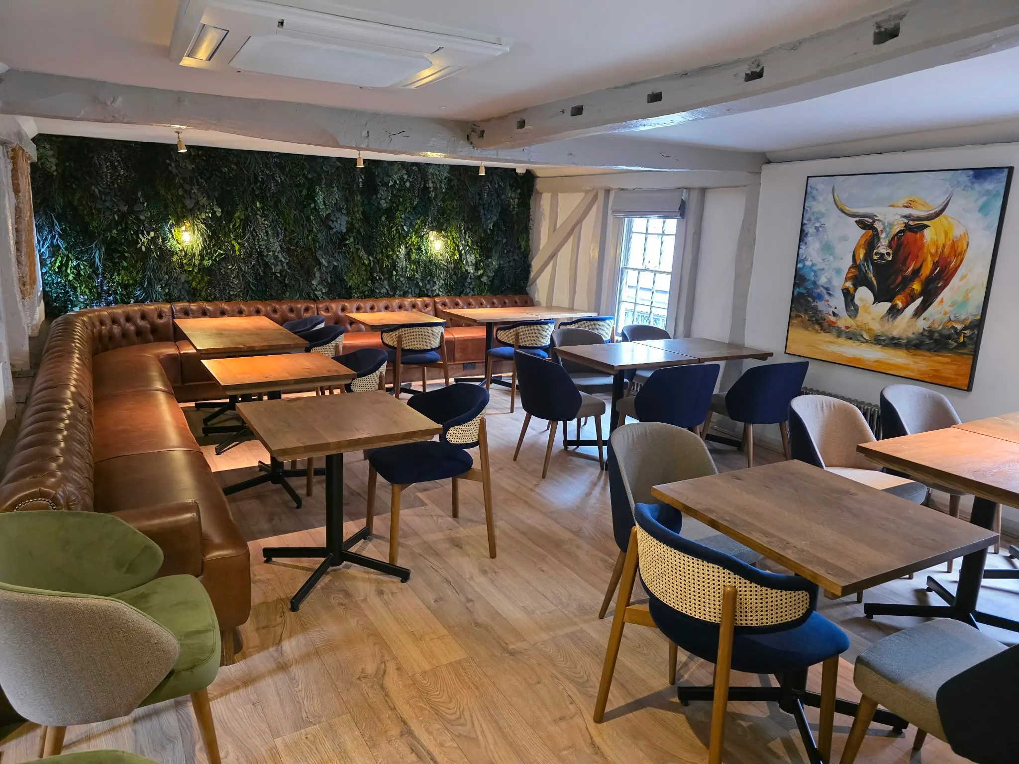 Restaurant dining room with leather banquettes, a living green wall and timber tables