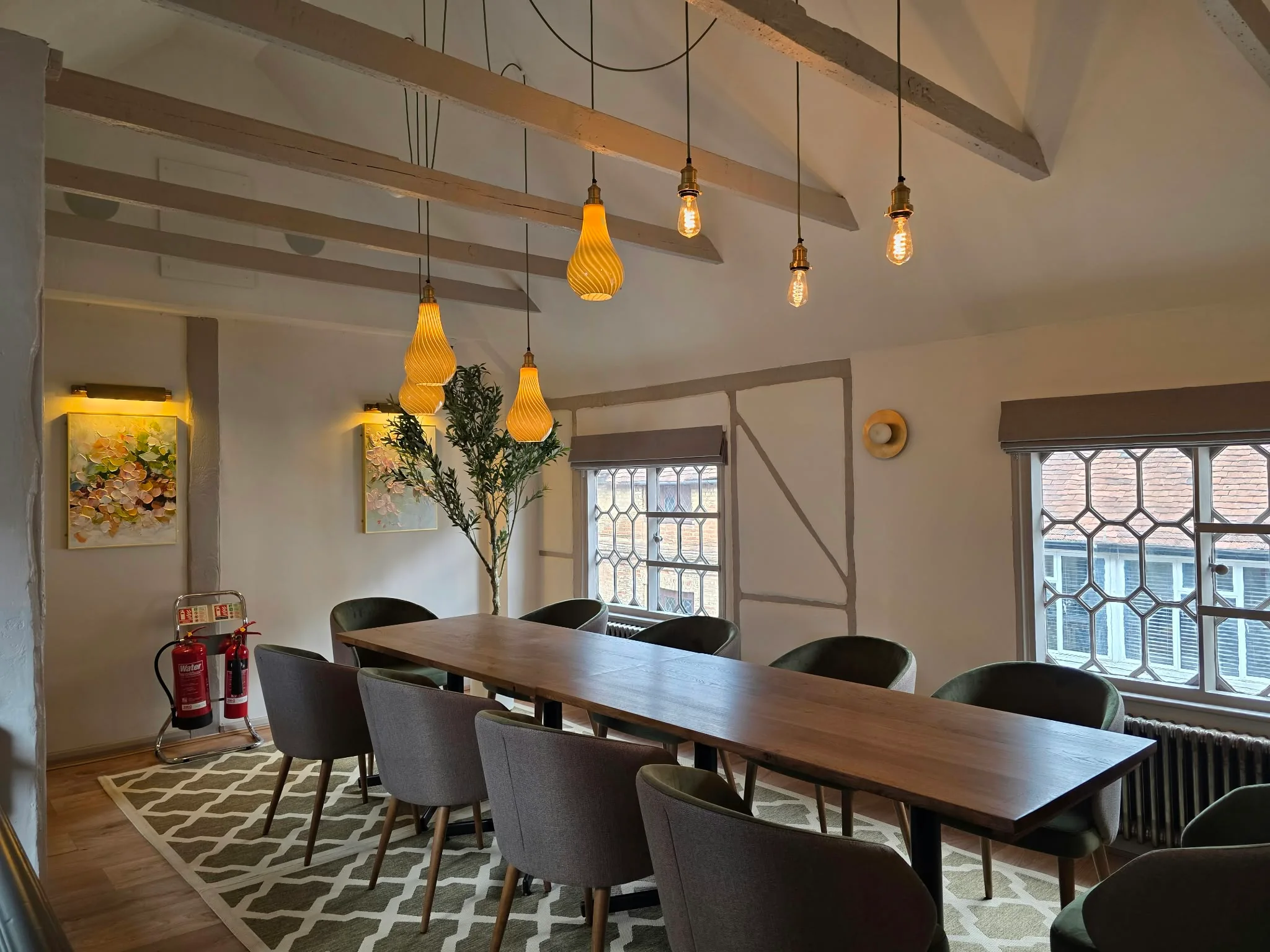 Private dining room with a long timber table, exposed beams and amber pendant lights