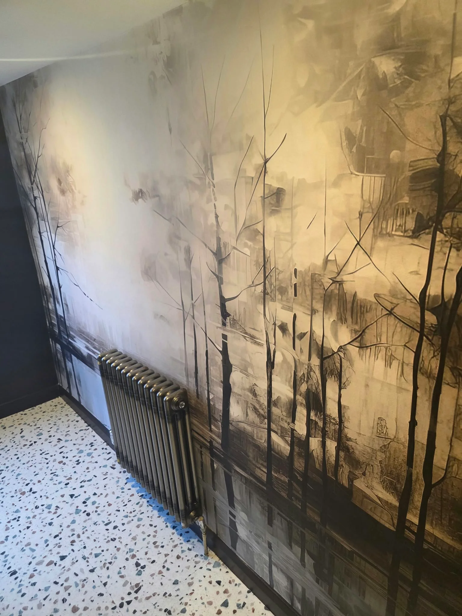 Forest mural wallpaper with terrazzo flooring and a cast-iron radiator
