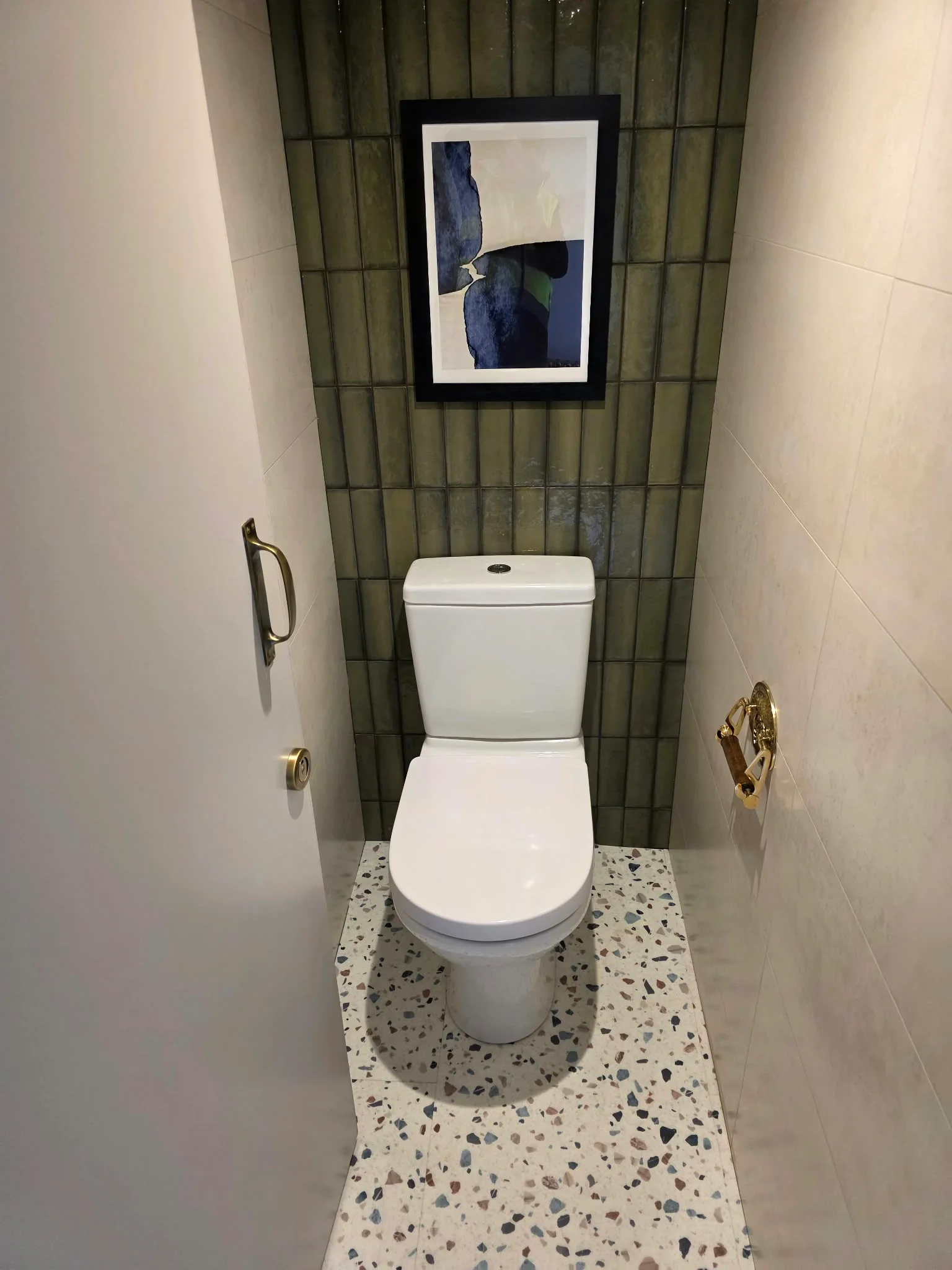WC with green tiled feature wall, terrazzo floor and brass fittings