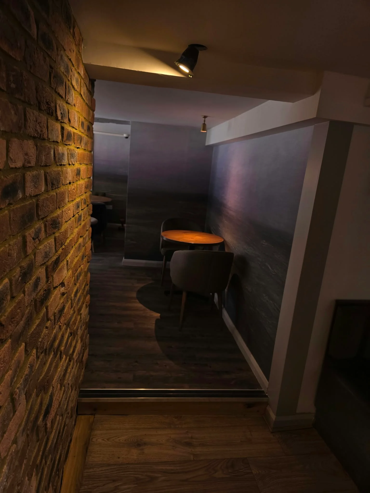 Dimly lit corridor with exposed brick leading to the dining room