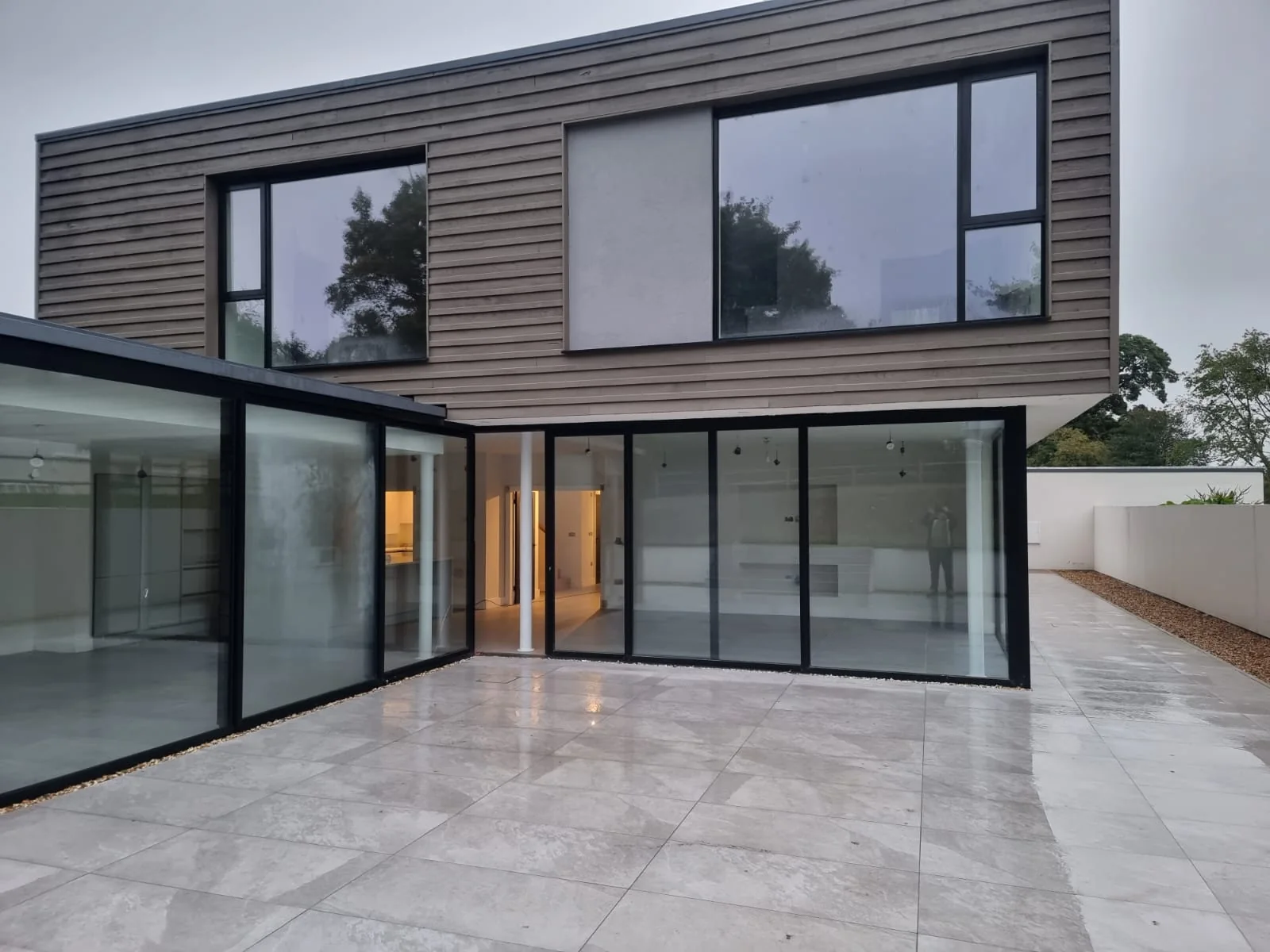 Modern timber-clad new-build house with large glazed corner and porcelain terrace