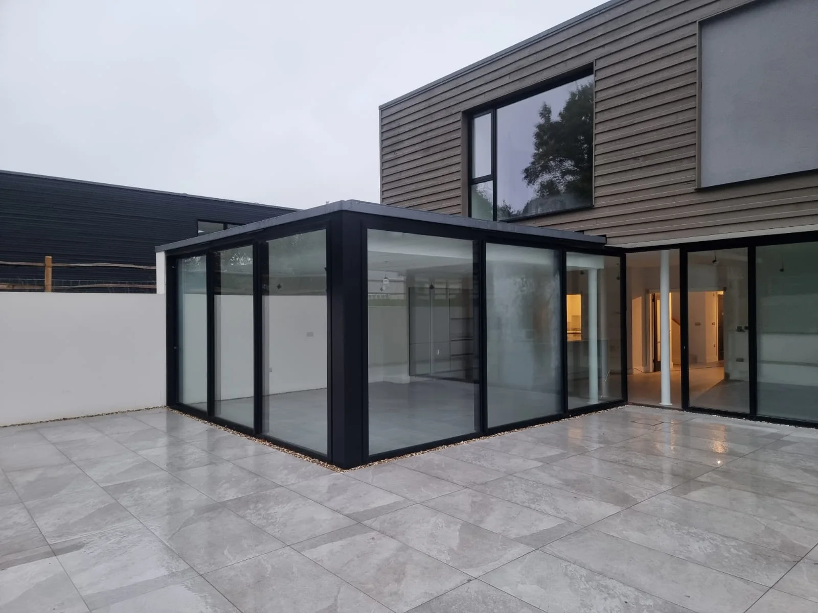 Glazed garden room with slim black frames opening onto the terrace