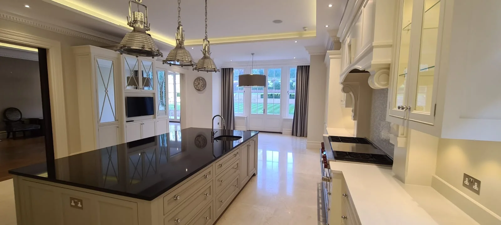 Bespoke cream kitchen with a black stone island and glass pendant lights, St John's Wood