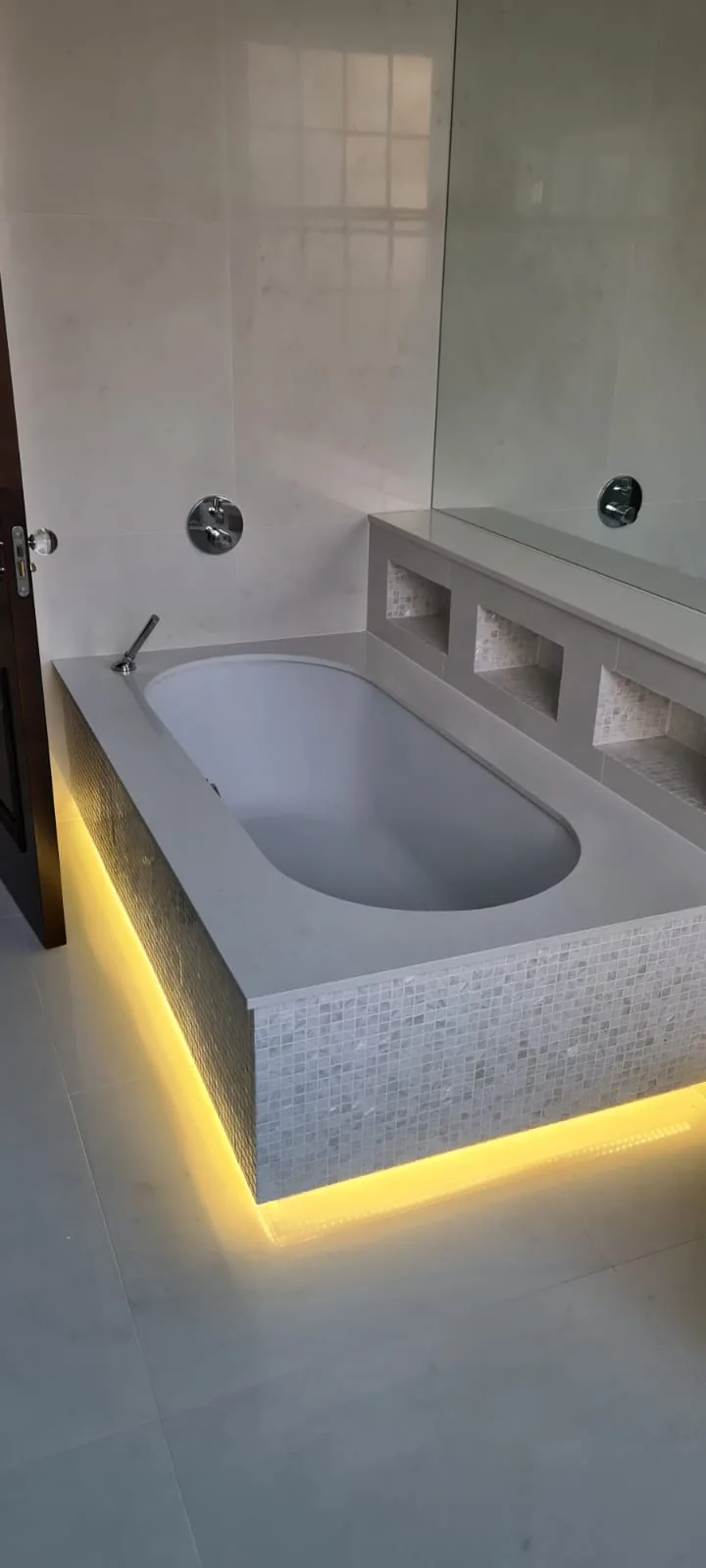 Inset bath with marble mosaic and concealed LED lighting