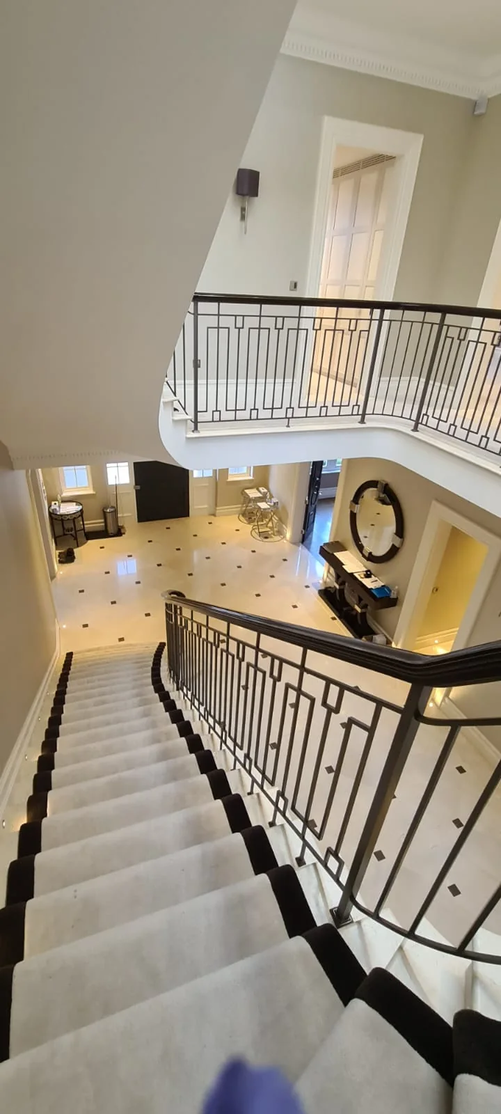 Sweeping staircase with a wrought-iron balustrade and marble hallway