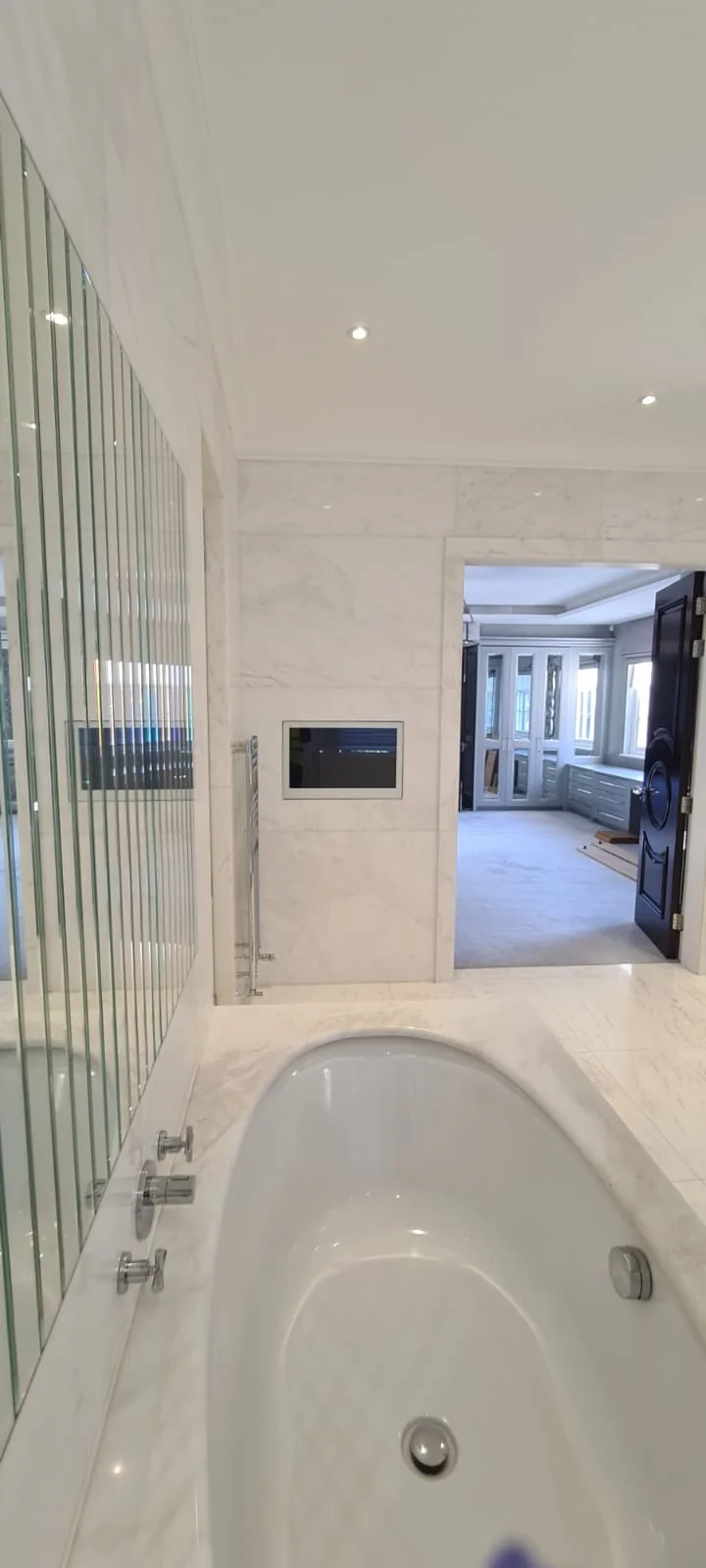 Marble bathroom with a built-in bath and mirrored wall