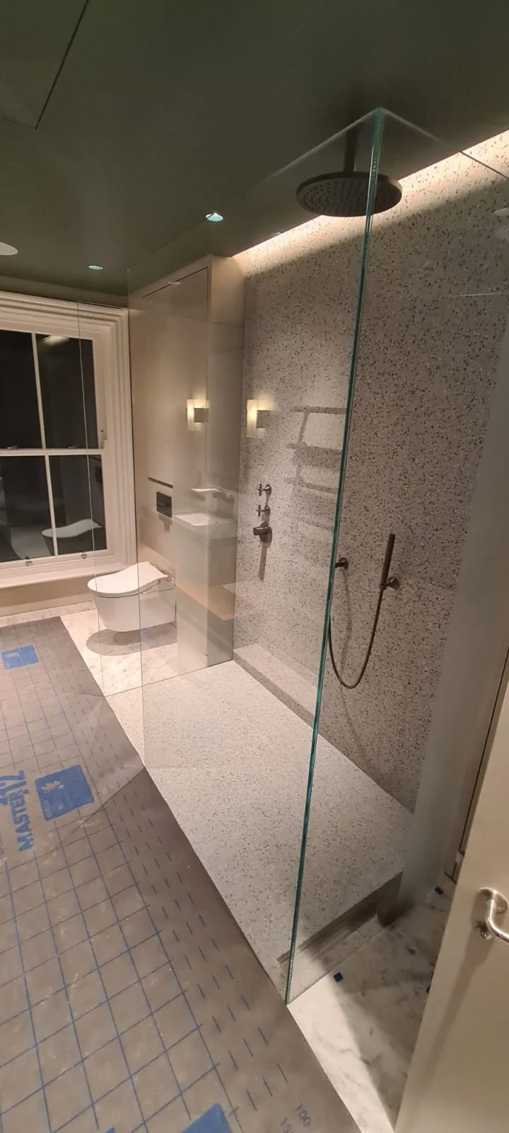 Walk-in glass shower enclosure with marble walls