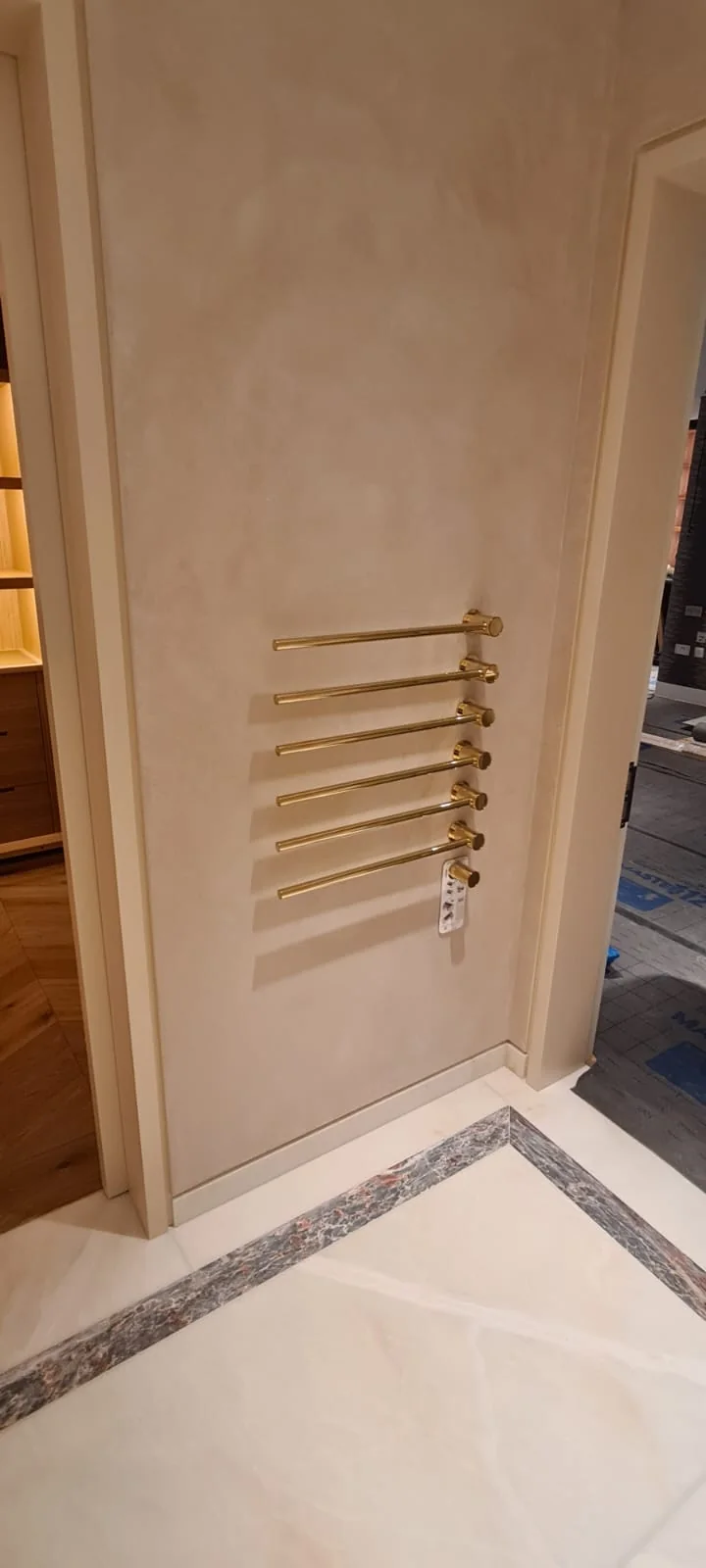 Polished brass towel rail against a polished plaster wall