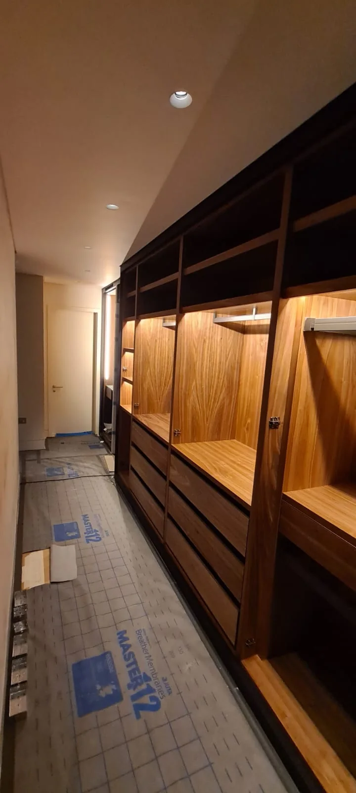 Walk-in dressing room with lit bespoke walnut joinery