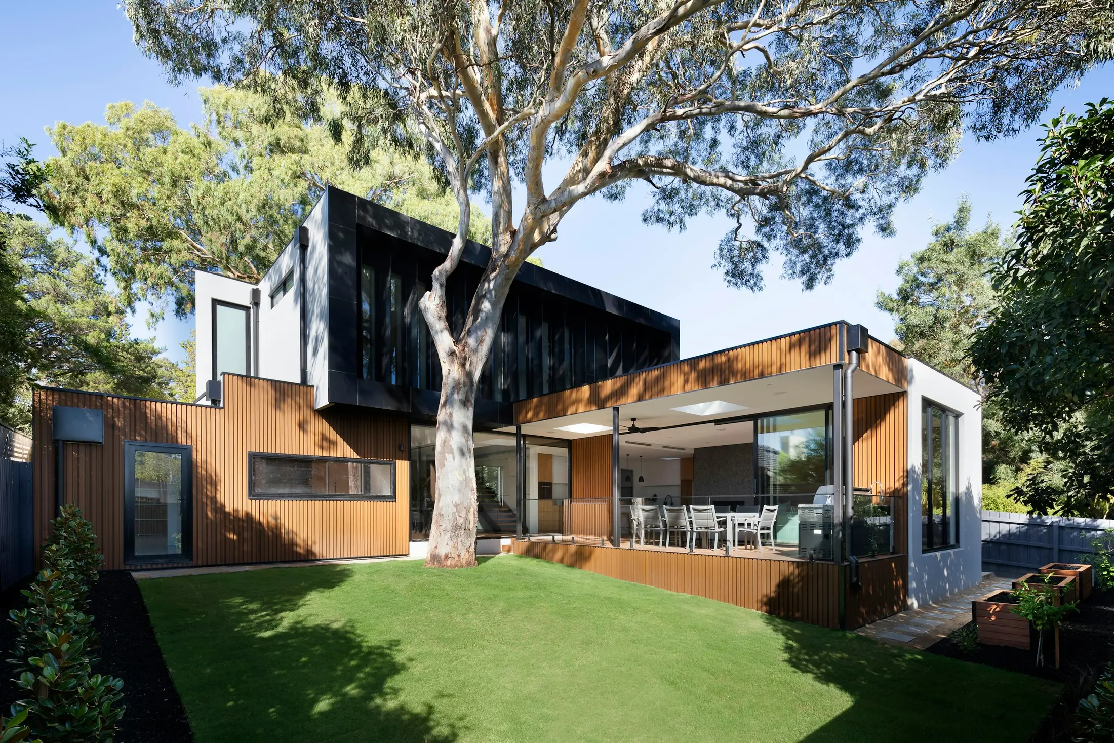 Dark contemporary façade with warm timber and lit glazing at dusk (stock image)