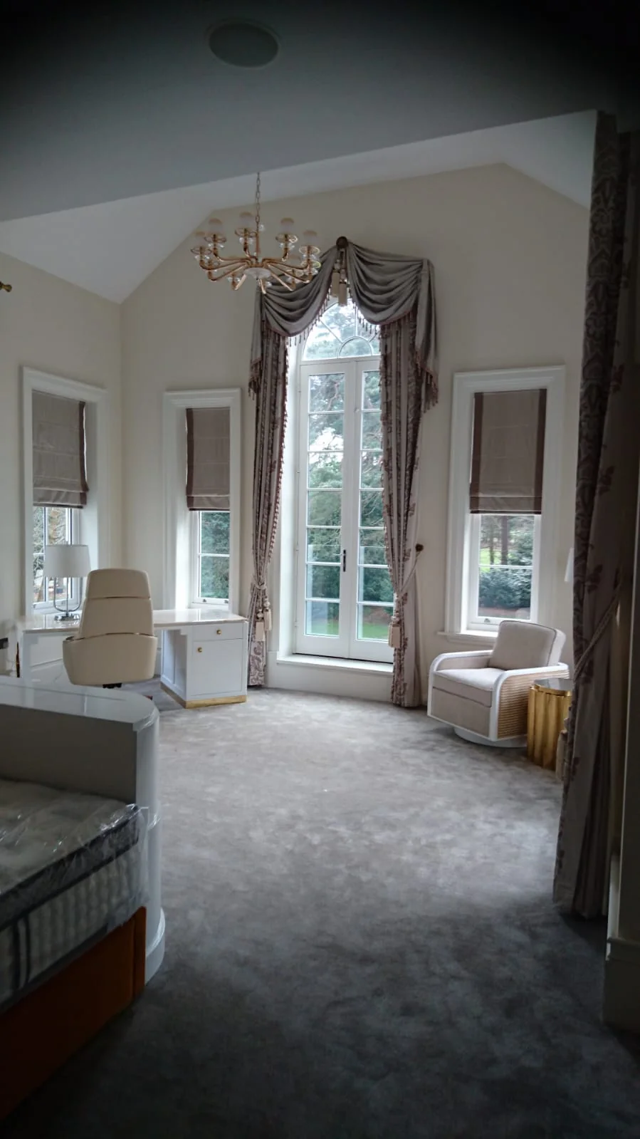 Bedroom with a vaulted ceiling, arched window and chandelier