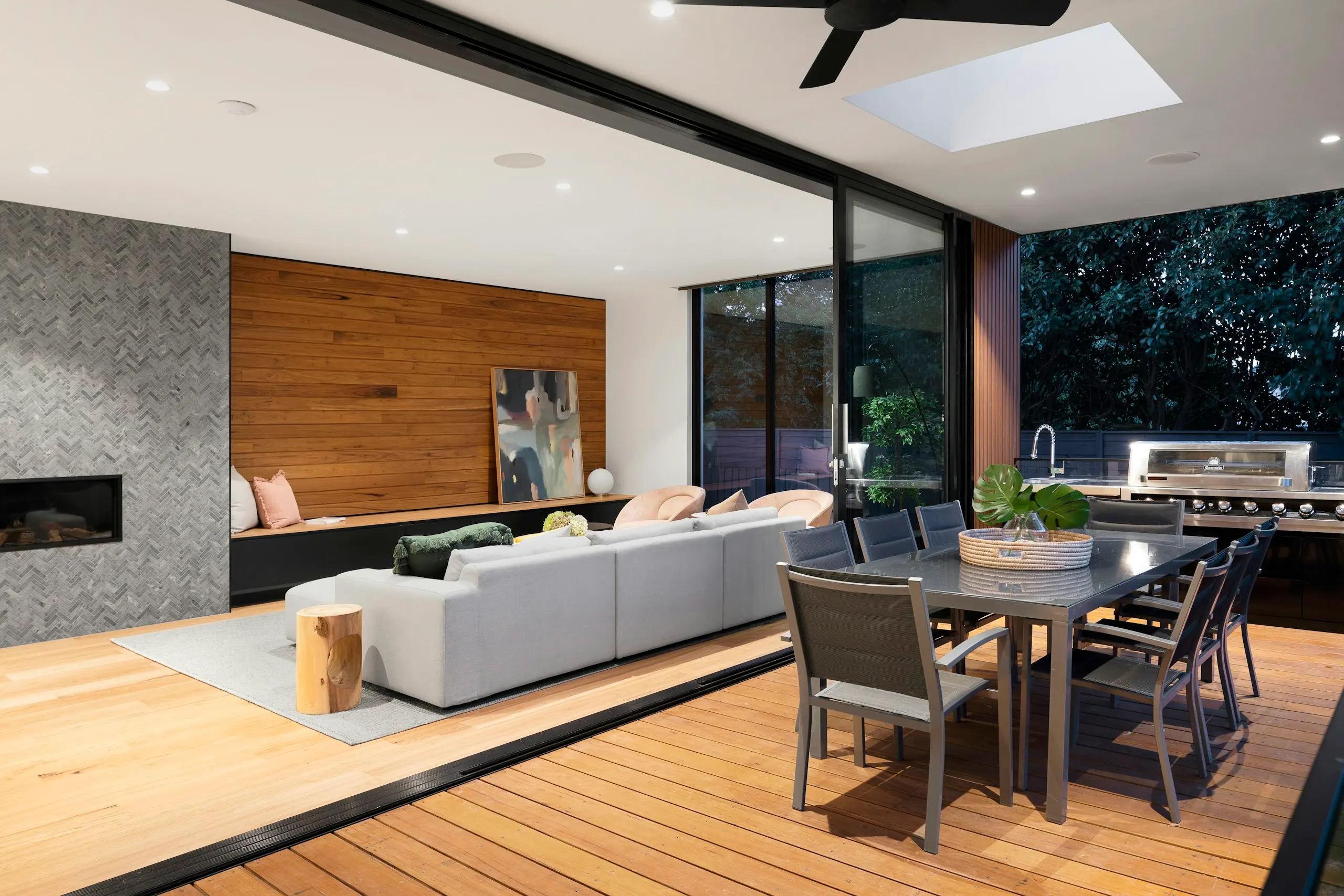 Open-plan living room with a stone fireplace wall and timber floors (stock image)